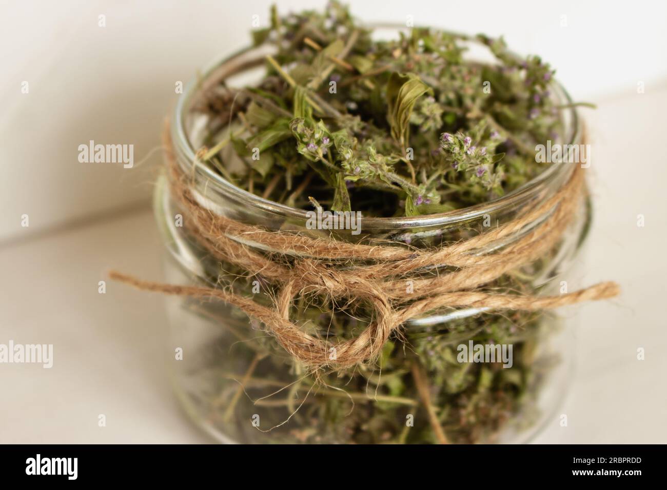 Timo essiccato in vaso di vetro su fondo di legno. Tè alle erbe in vaso. Concetto di prodotti ecologici. Cibo sano. Tè alle erbe fatto in casa. Timo secco con fiori. Foto Stock