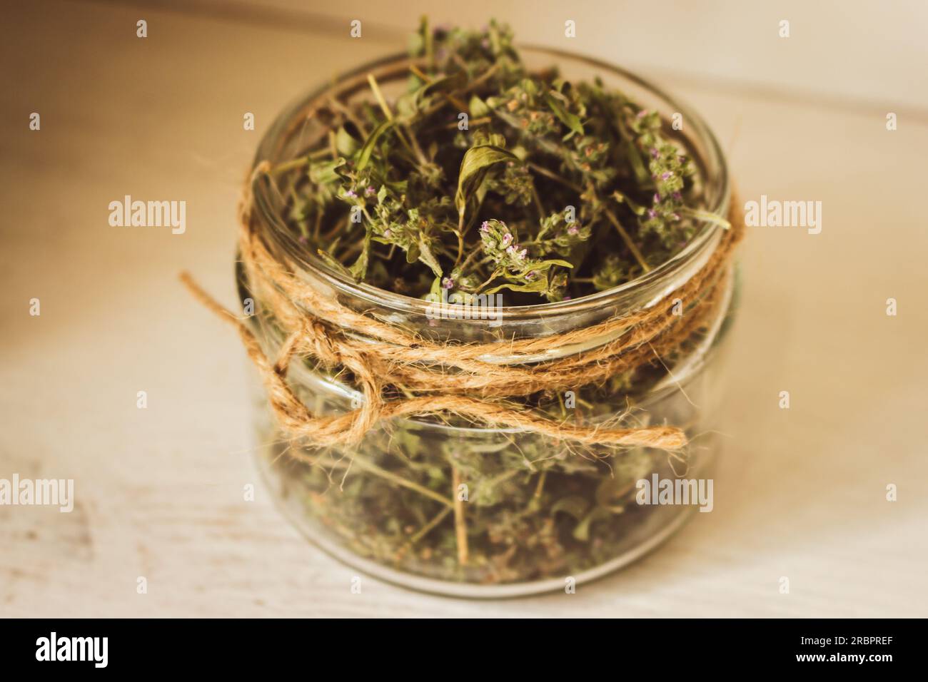 Timo essiccato in vaso di vetro su fondo di legno. Tè alle erbe in vaso. Concetto di prodotti ecologici. Cibo sano. Tè alle erbe fatto in casa. Timo secco con fiori. Foto Stock