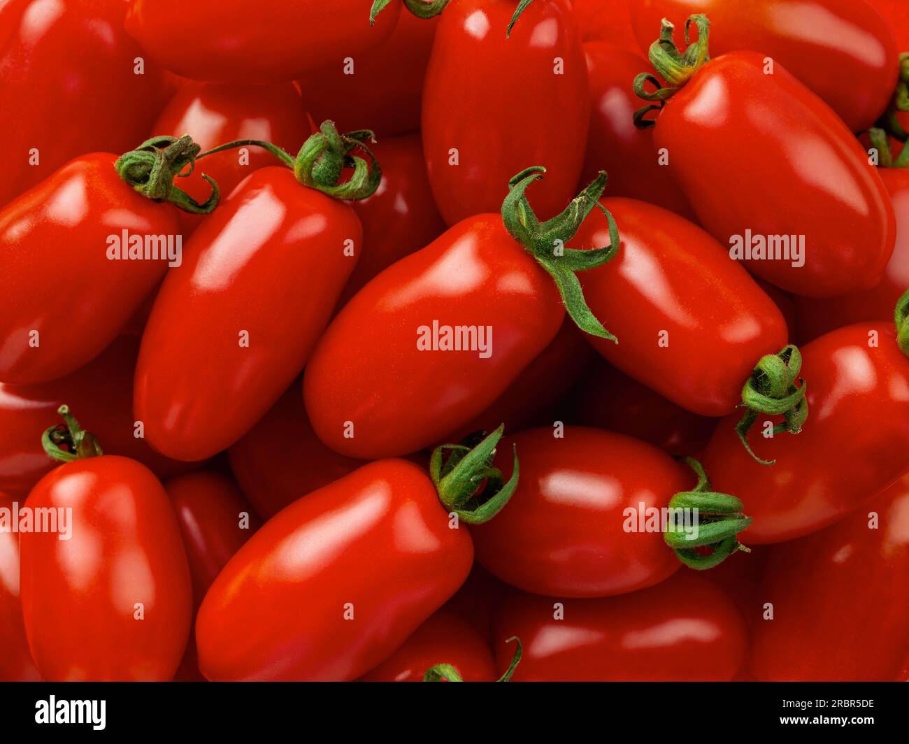 Fondale macro di pomodori ciliegini Ornela crudo. Consistenza di piccoli pomodori a forma di bottiglia. Primo piano di verdure biologiche mature. Mangiare sano cibo vegetariano Foto Stock