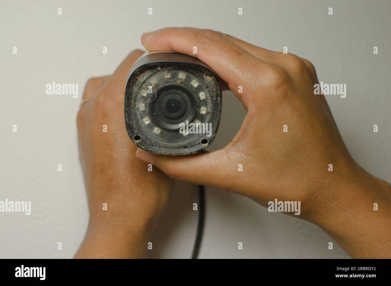 Tecnico qualificato che esegue la manutenzione di una telecamera di sicurezza bianca, rafforzando l'aspetto della protezione e della sorveglianza. Foto Stock