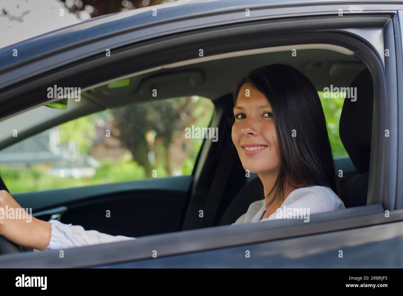 Donna che guida un'auto e sorride Foto Stock