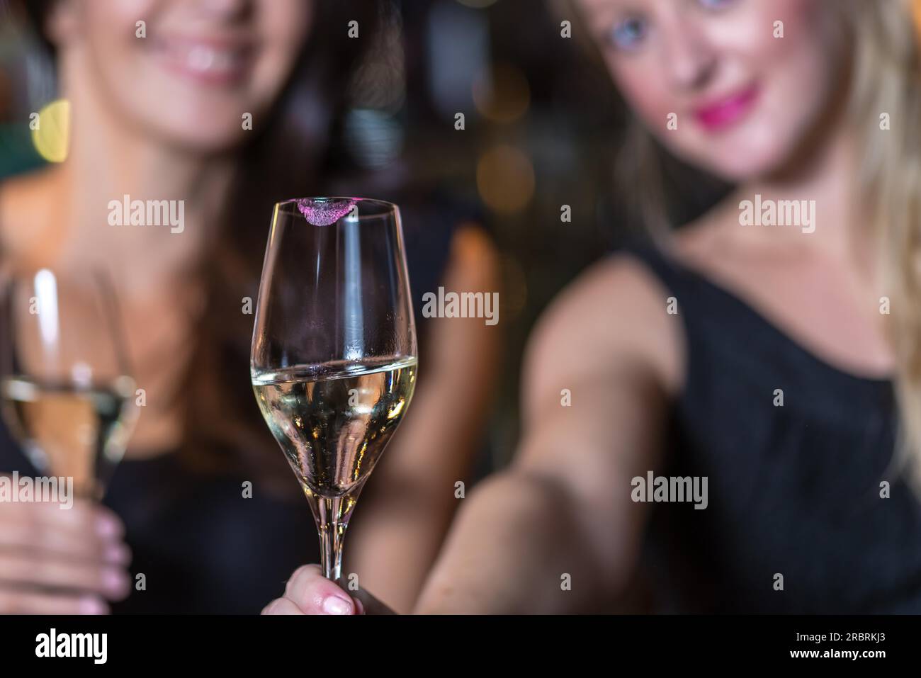 Le donne sorridenti festeggiano con champagne in un ristorante o in un nightclub mentre fanno festa con un bicchiere elegante di champagne nel Foto Stock
