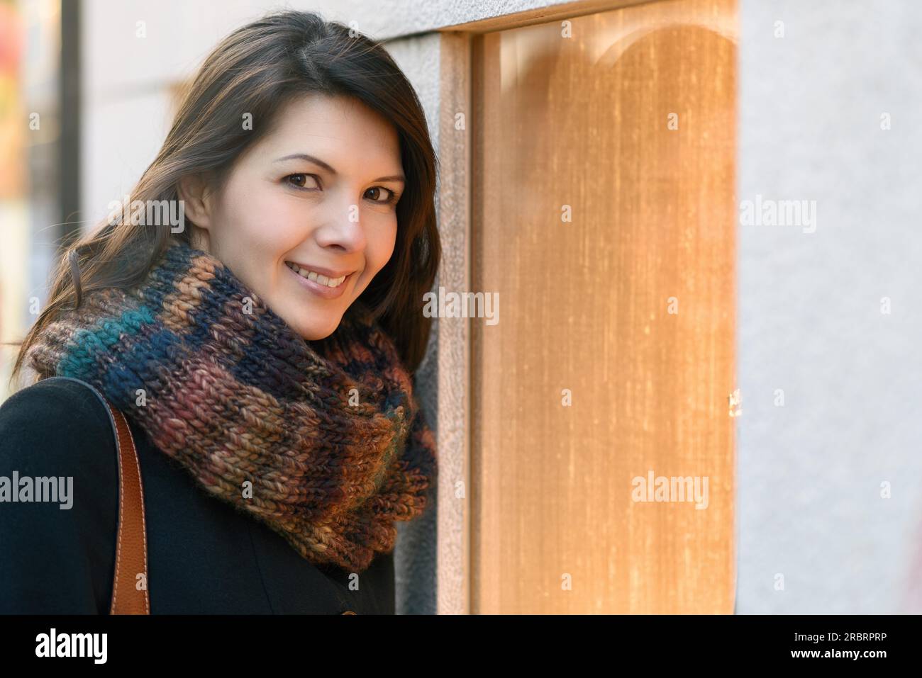 Brunette donna attraente shopping in inverno, di fronte a una finestra del negozio, sorridente verso la telecamera Foto Stock