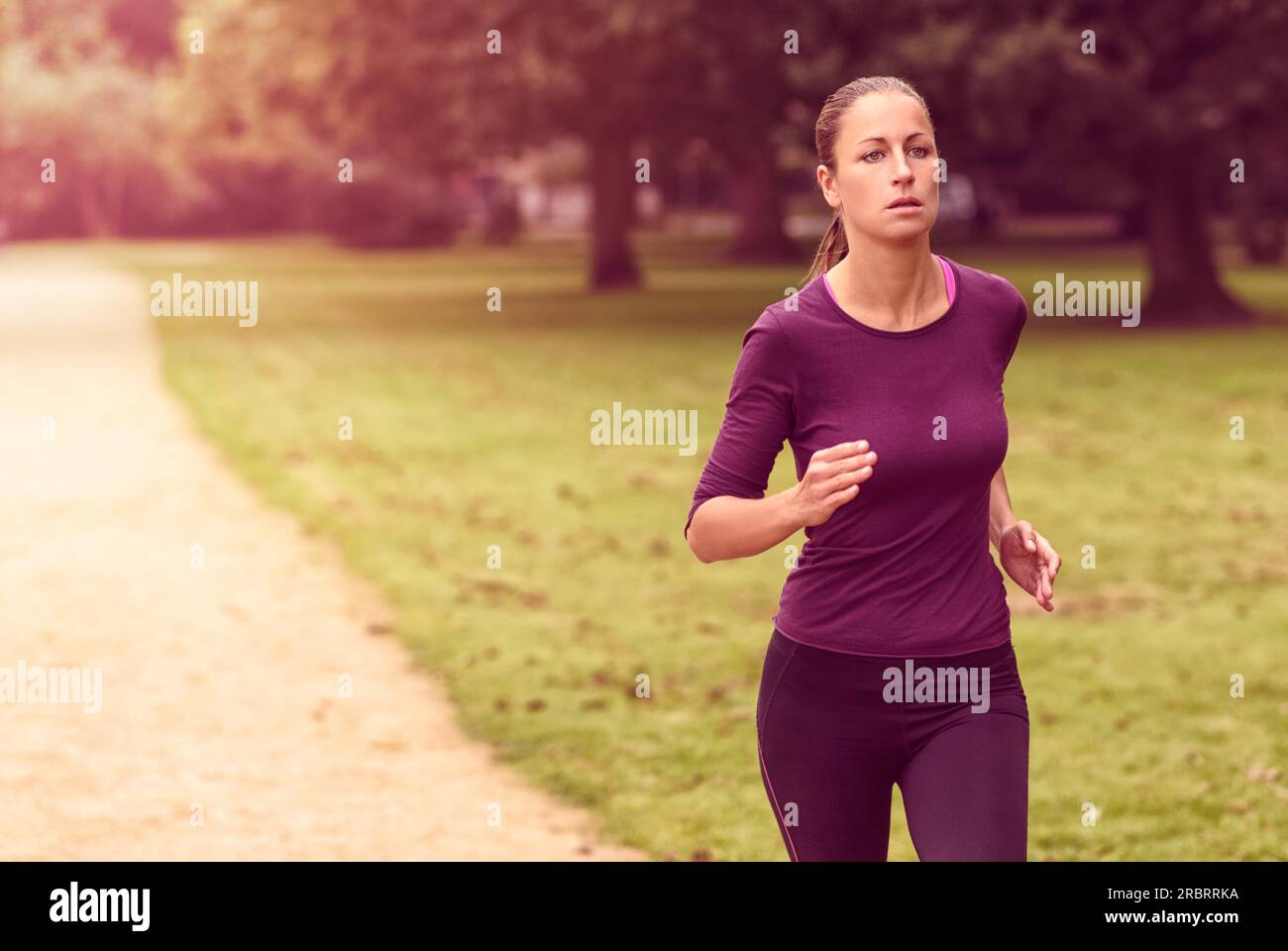 Half Body Shot di una donna atletica che fa un esercizio di corsa al parco con una seria espressione facciale Foto Stock