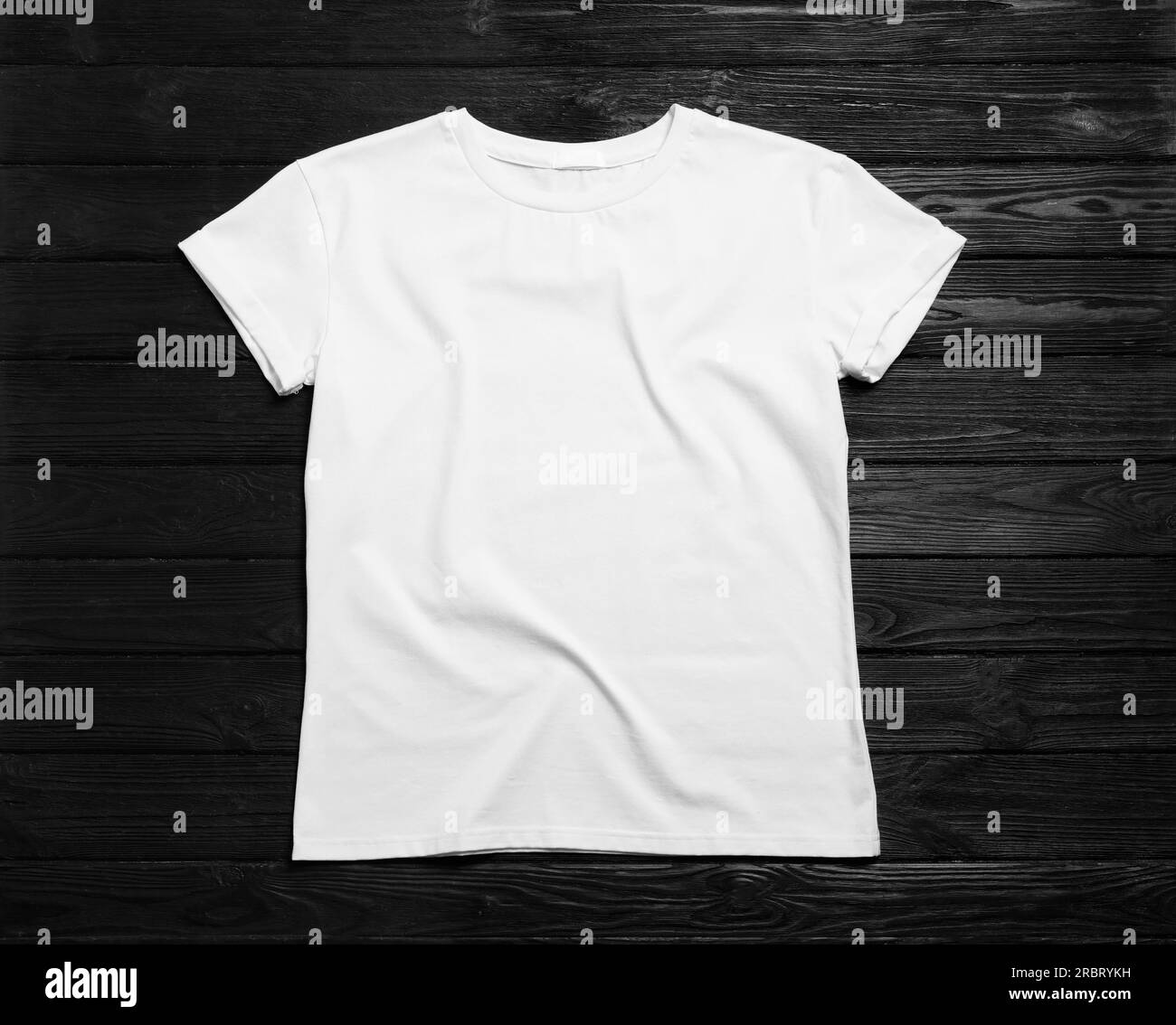Elegante t-shirt bianca su sfondo in legno nero, vista dall'alto Foto Stock
