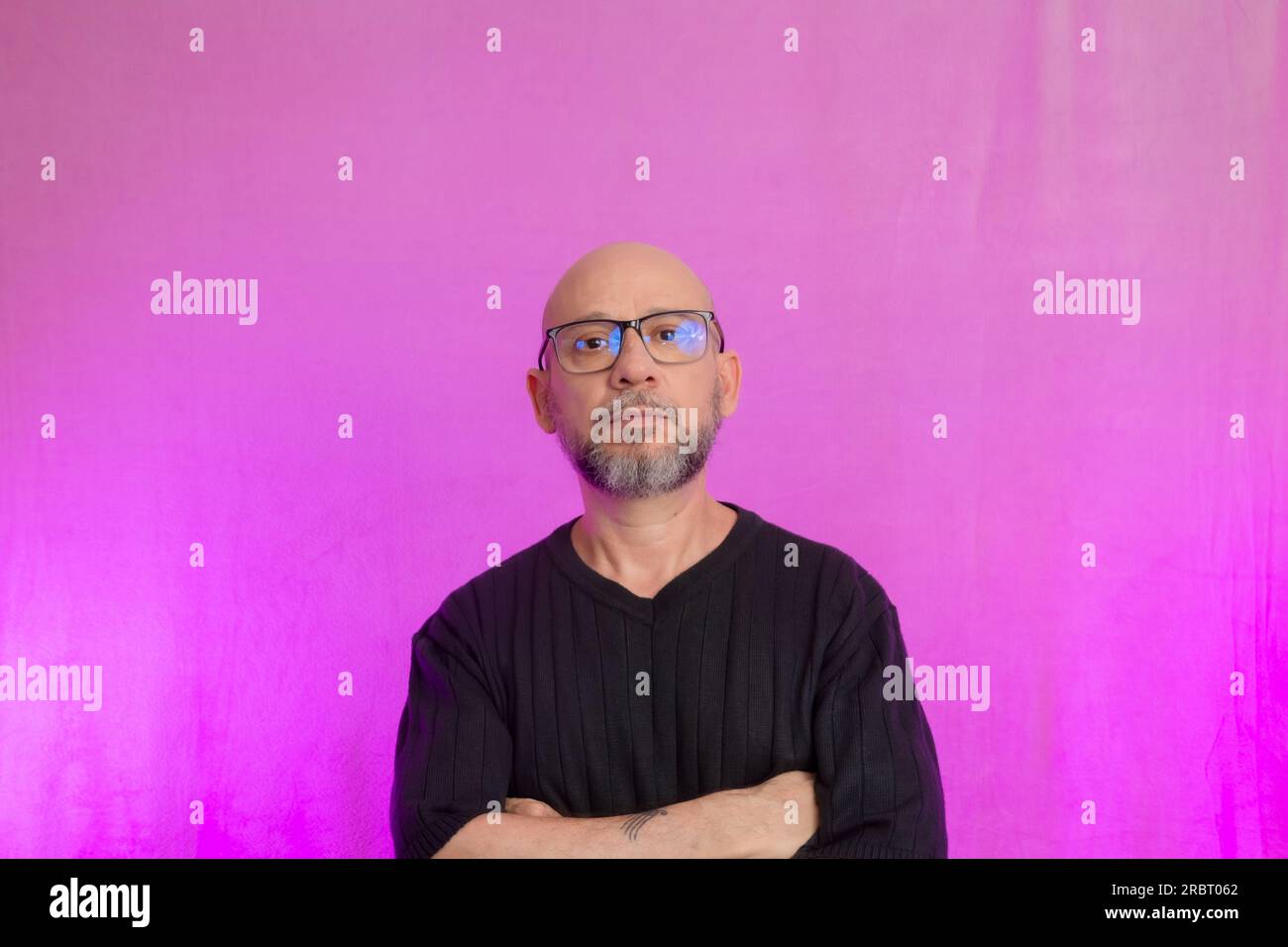 Ritratto di un serio uomo di 50 anni con barba e testa calva. Isolato su sfondo rosa. Foto Stock