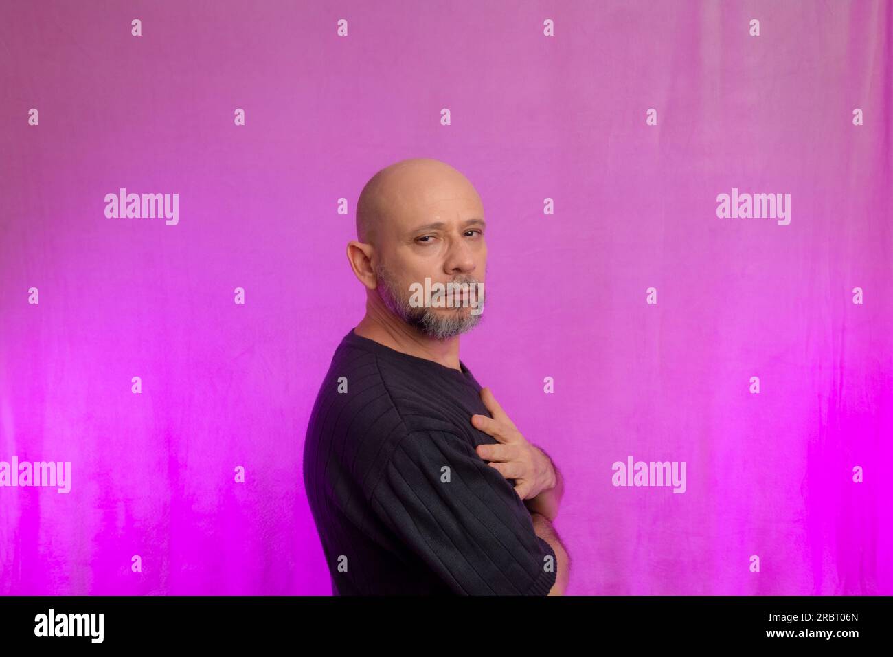 Ritratto di un serio uomo di 50 anni con barba e testa calva. Isolato su sfondo rosa. Foto Stock