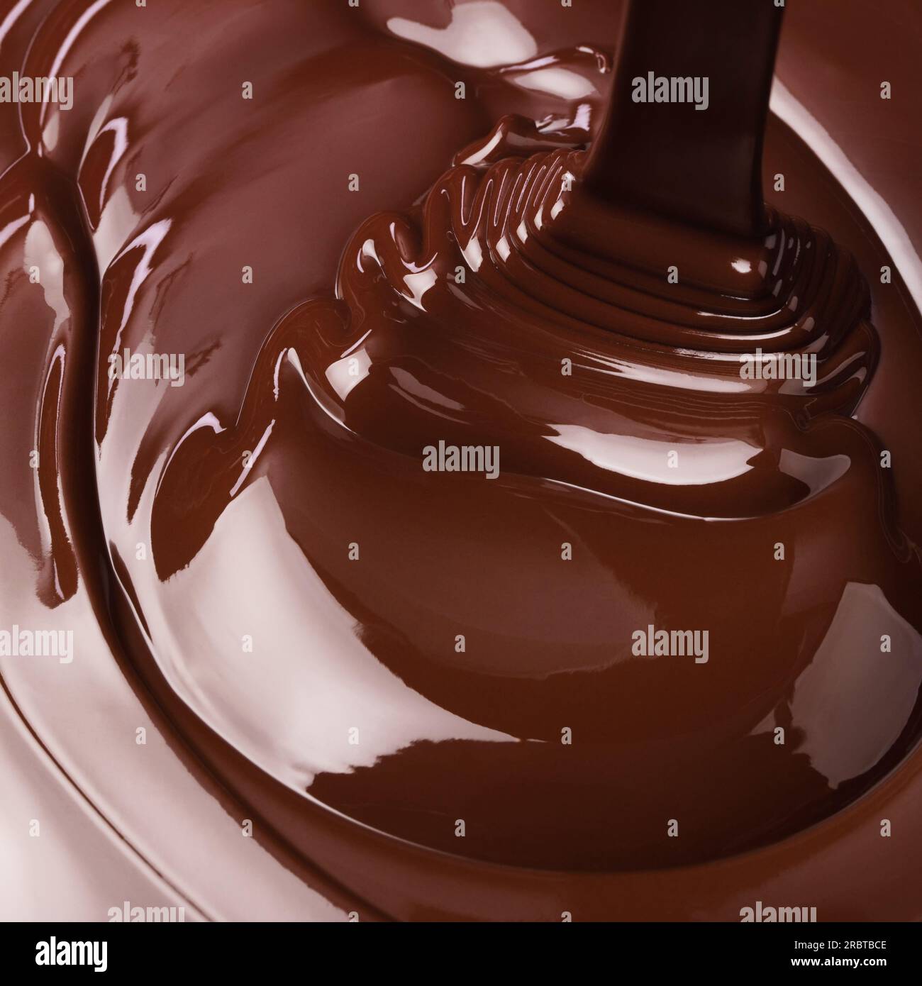 il flusso di cioccolato fuso si diffonde in onde. fondo di cioccolata calda Foto Stock