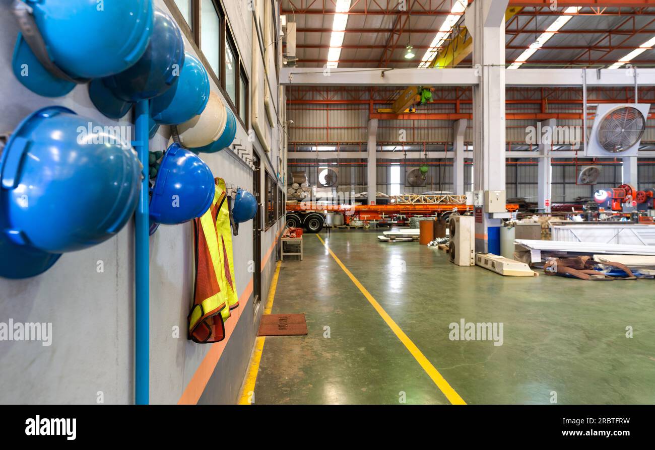 Atmosfera nella fabbrica di lamiere. Elmetto da costruzione e giubbotto di sicurezza per supervisori e dipendenti appesi di fronte al negozio dell'ufficio della fabbrica per sa Foto Stock