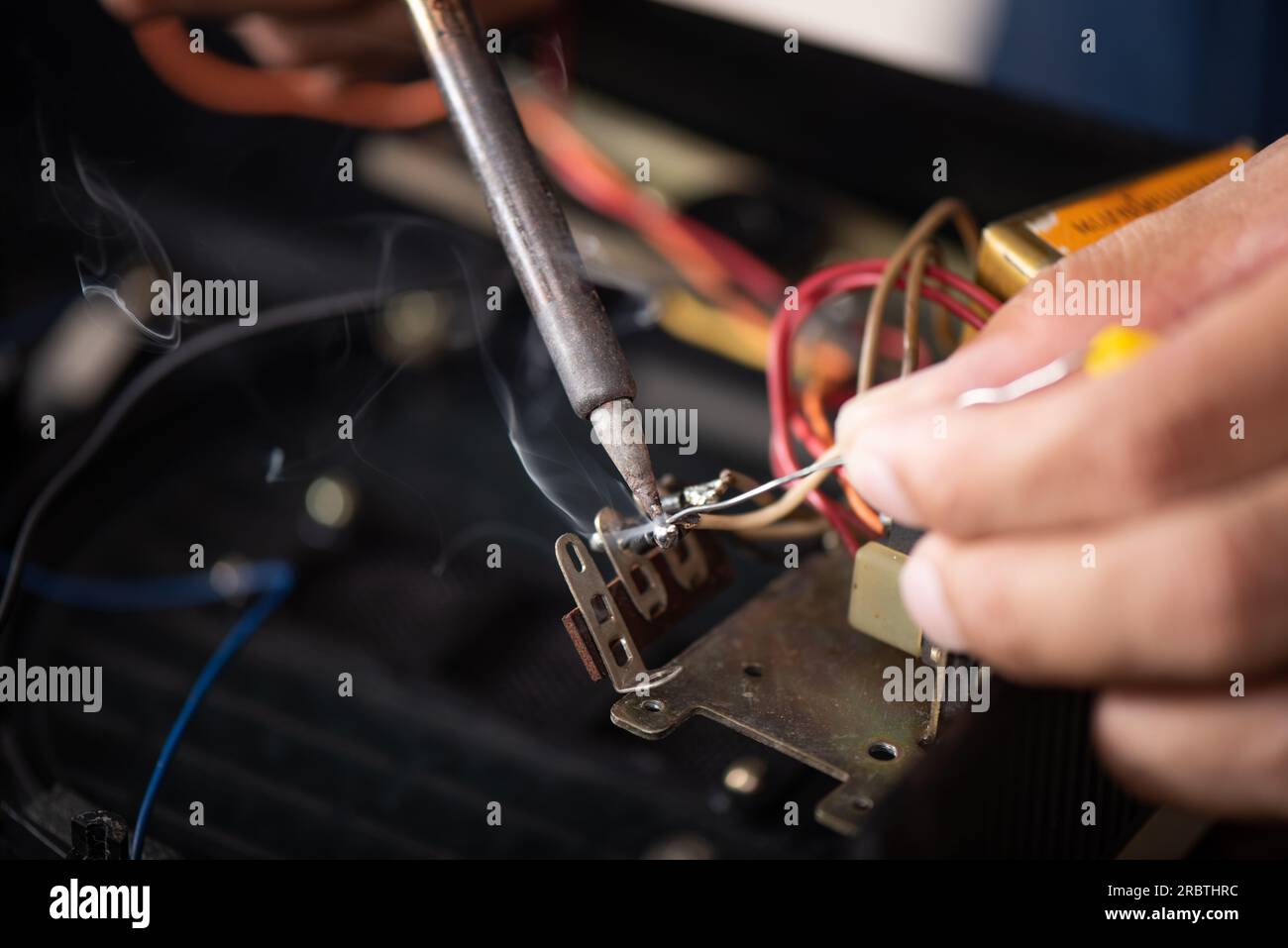 Tecnico che utilizza il saldatore per riparare il dispositivo elettronico. Foto Stock