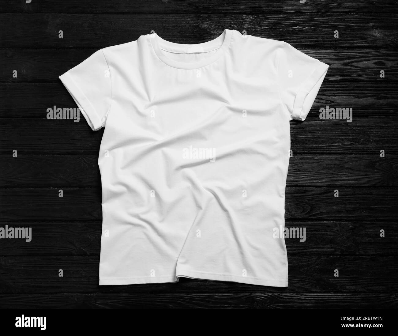 Elegante t-shirt bianca su sfondo in legno nero, vista dall'alto Foto Stock