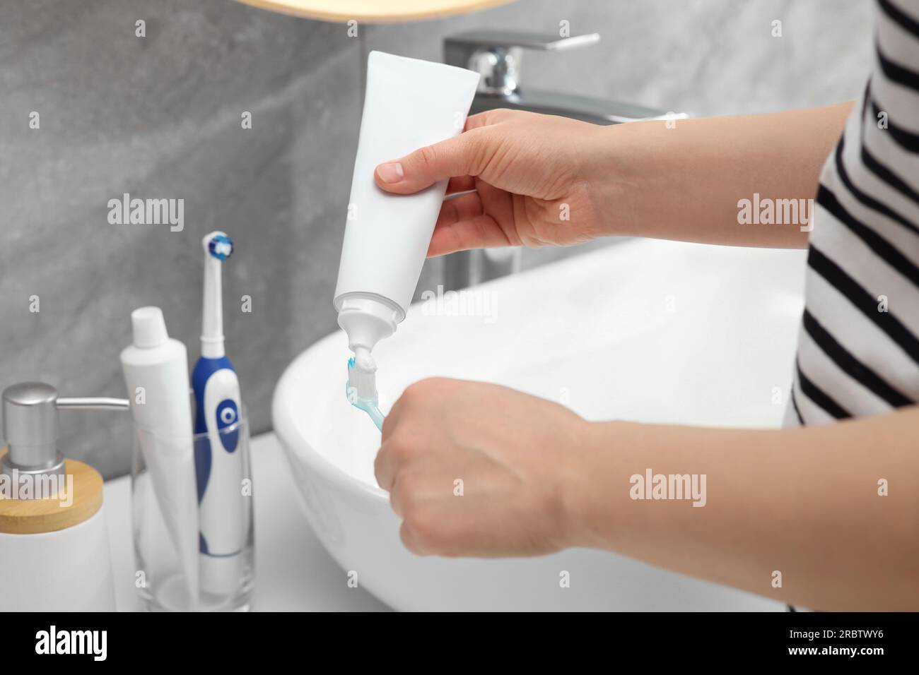 Donna che strizza dentifricio dal tubo allo spazzolino vicino al lavandino  in bagno, primo piano Foto stock - Alamy