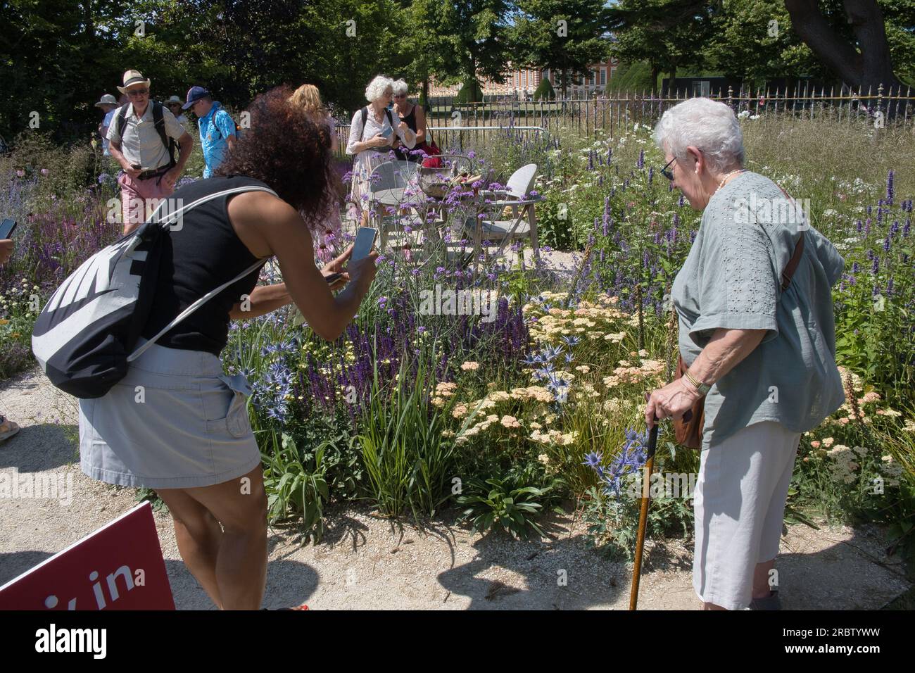 I visitatori ammirano uno dei giardini dello spettacolo al RHS Hampton Court Flower Show di Londra Foto Stock