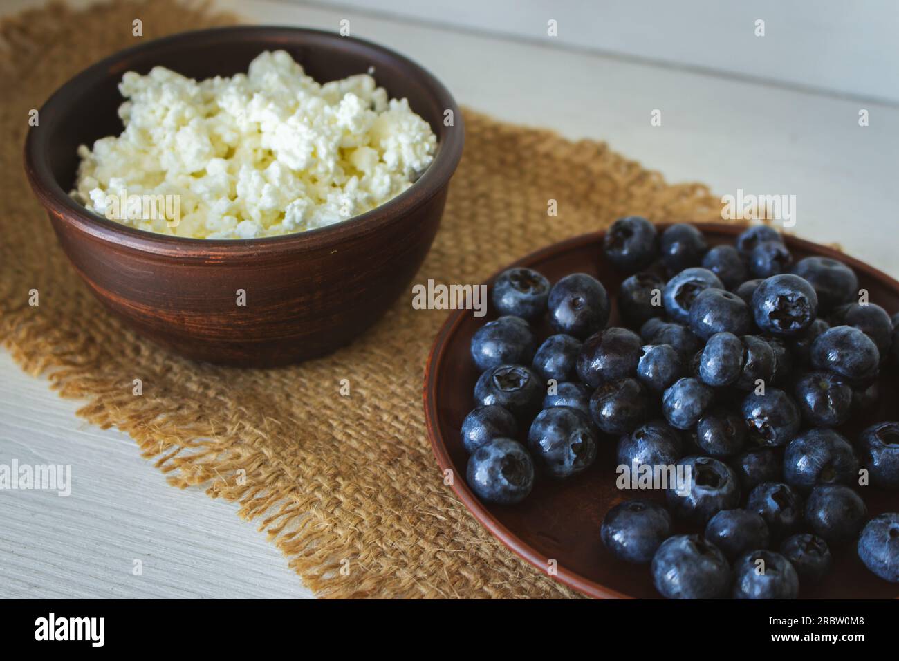 Formaggio cottage con mirtilli. Colazione salutare. Riccio in ciotola con frutti di bosco dolci. Cibo biologico agricolo. Formaggio casalingo fatto in casa con frutti di bosco. Foto Stock