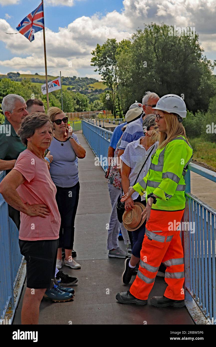 Helen del Canal and River Trust sta rispondendo alle domande di un gruppo di visitatori in un giorno pubblico aperto per i lavori di riparazione del bacino idrico di Toddbrook Foto Stock