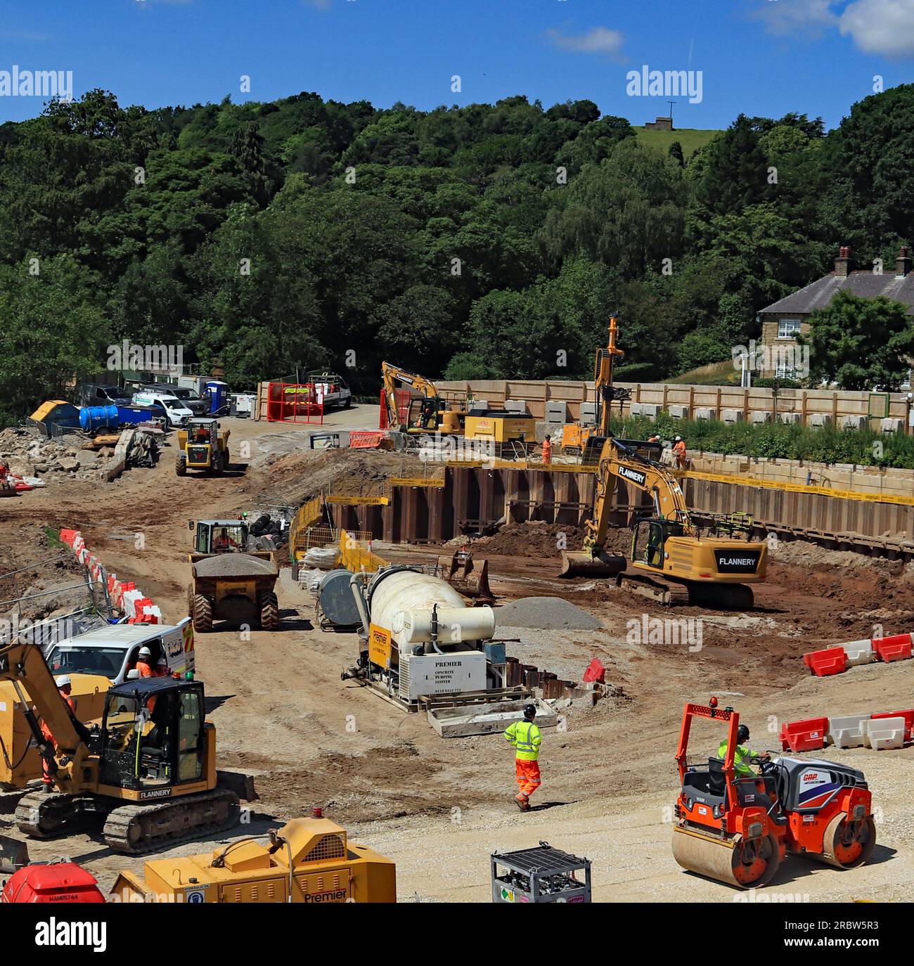 Vista dalla parte superiore della diga di Toddbrook mentre un escavatore sta scavando terra per prepararsi alla costruzione della nuova area di rotolamento con riparazioni alla diga Foto Stock