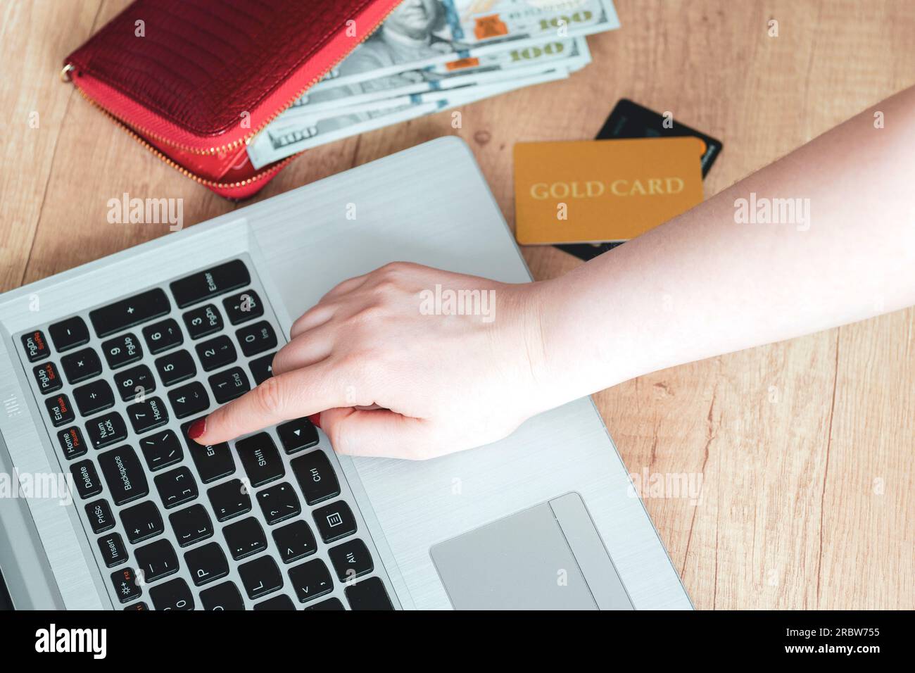 Premere manualmente il tasto invio sullo sfondo del laptop. Mano, portafoglio, soldi, portatile, carta d'oro, carte. Concept Scegli e acquista prodotti online. Shopper. concetto Foto Stock
