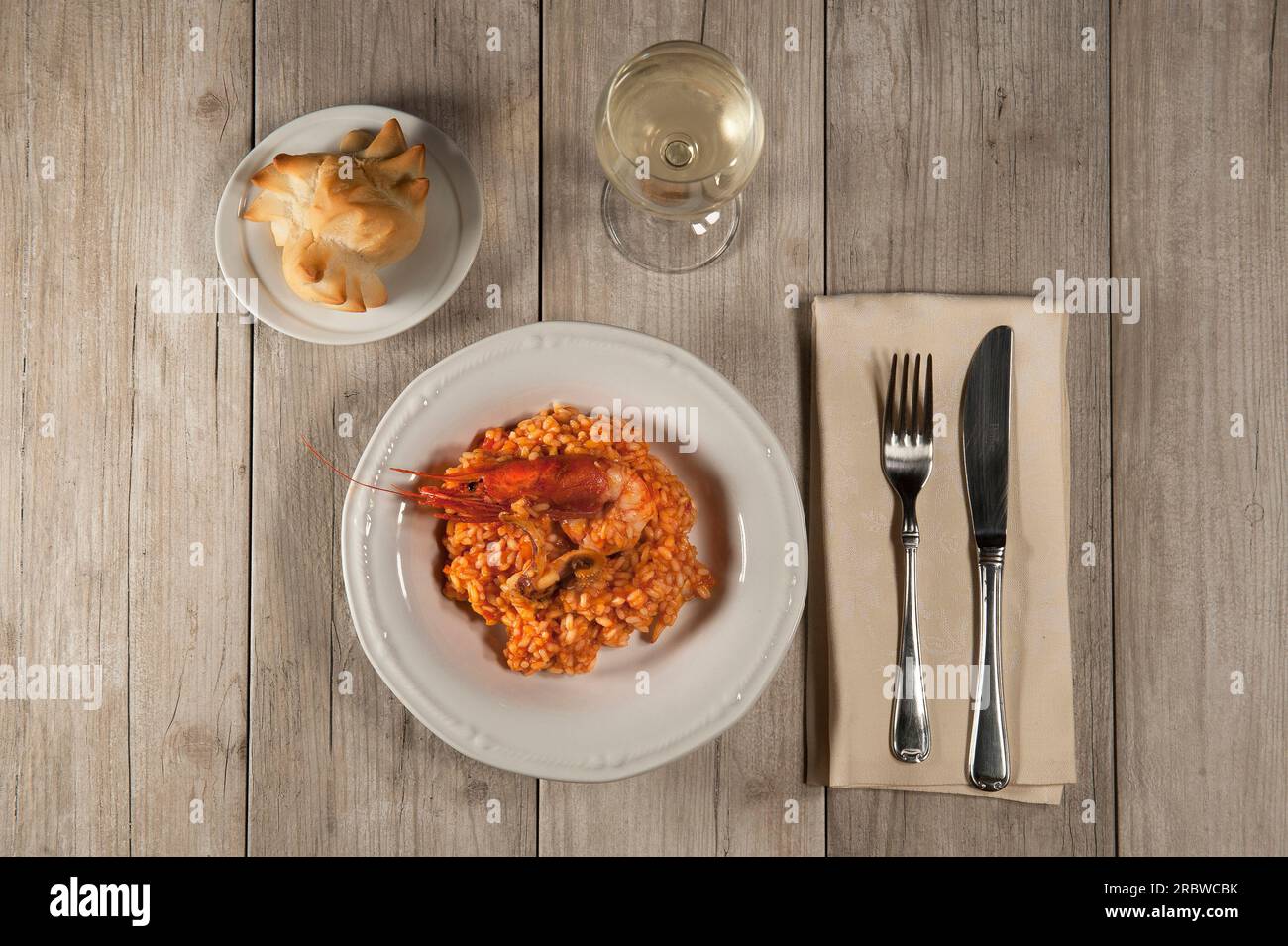 Risotto con gamberoni rossi, calamari, filetti di pesce, pomodoro. Pane e vino bianco. Dopo la cottura Foto Stock