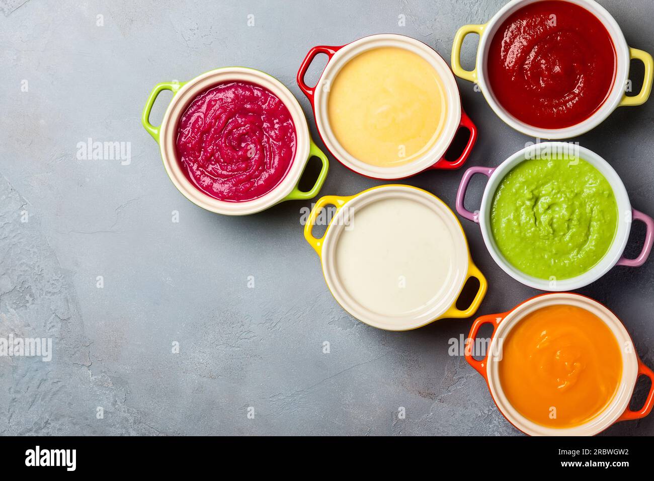 Varieta' di minestre di verdure colorate con panna in pentole piccole. Vista dall'alto. Concetto di alimentazione sana o cibo vegetariano. Foto Stock
