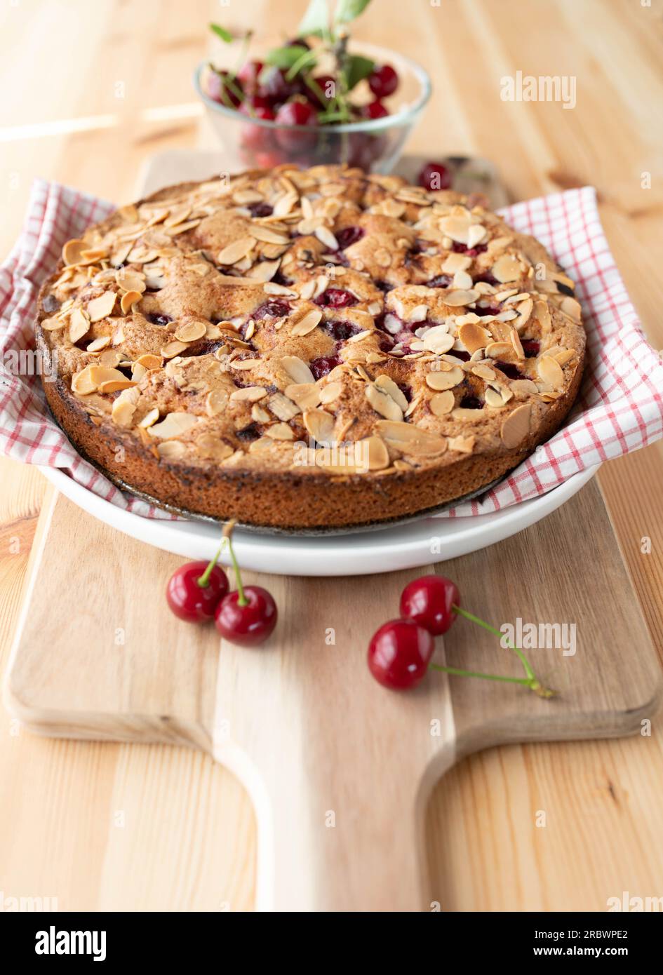 Torta di ciliegie o torta di ciliegie con mandorle e ciliegie acide su un tavolo di legno chiaro Foto Stock