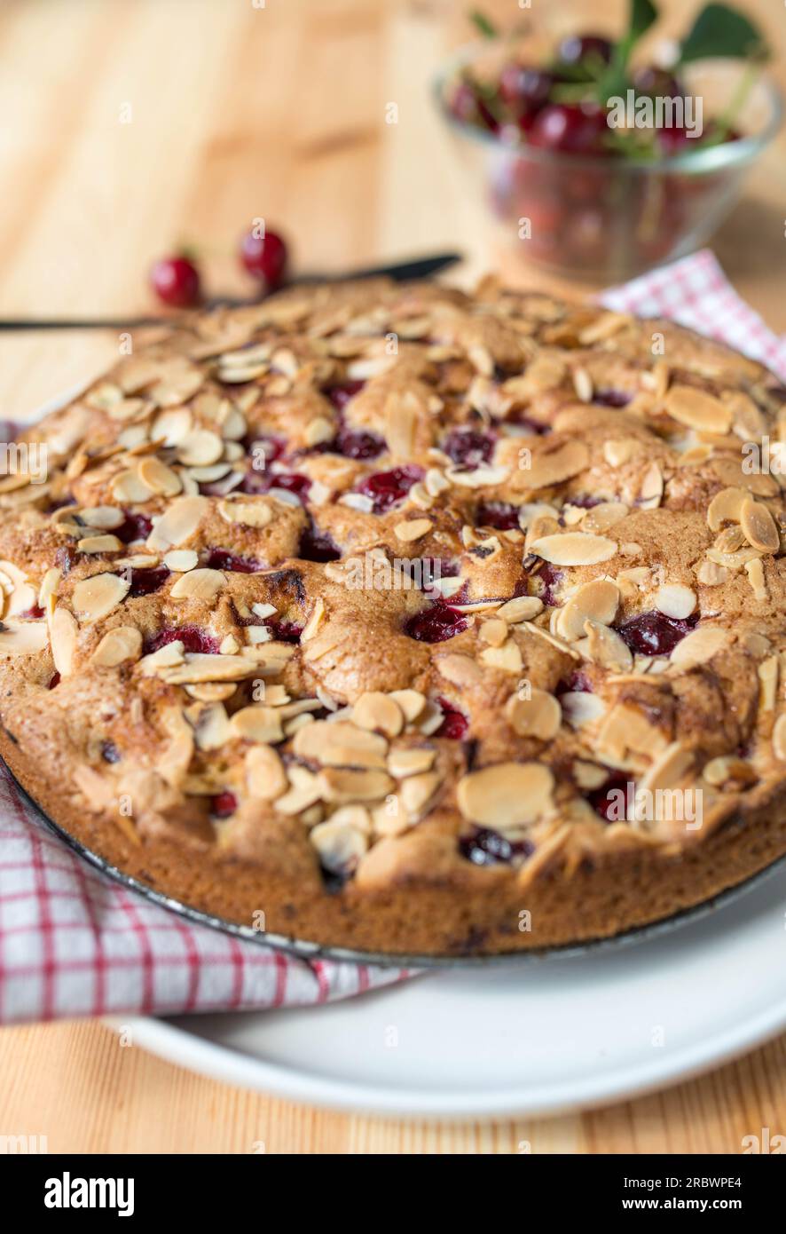 Torta di ciliegie o torta di ciliegie con mandorle e ciliegie acide su un tavolo di legno chiaro Foto Stock