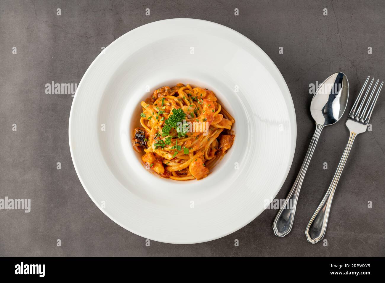 Spaghetti di gamberi su piatto di porcellana bianca su tavolo in pietra nera Foto Stock