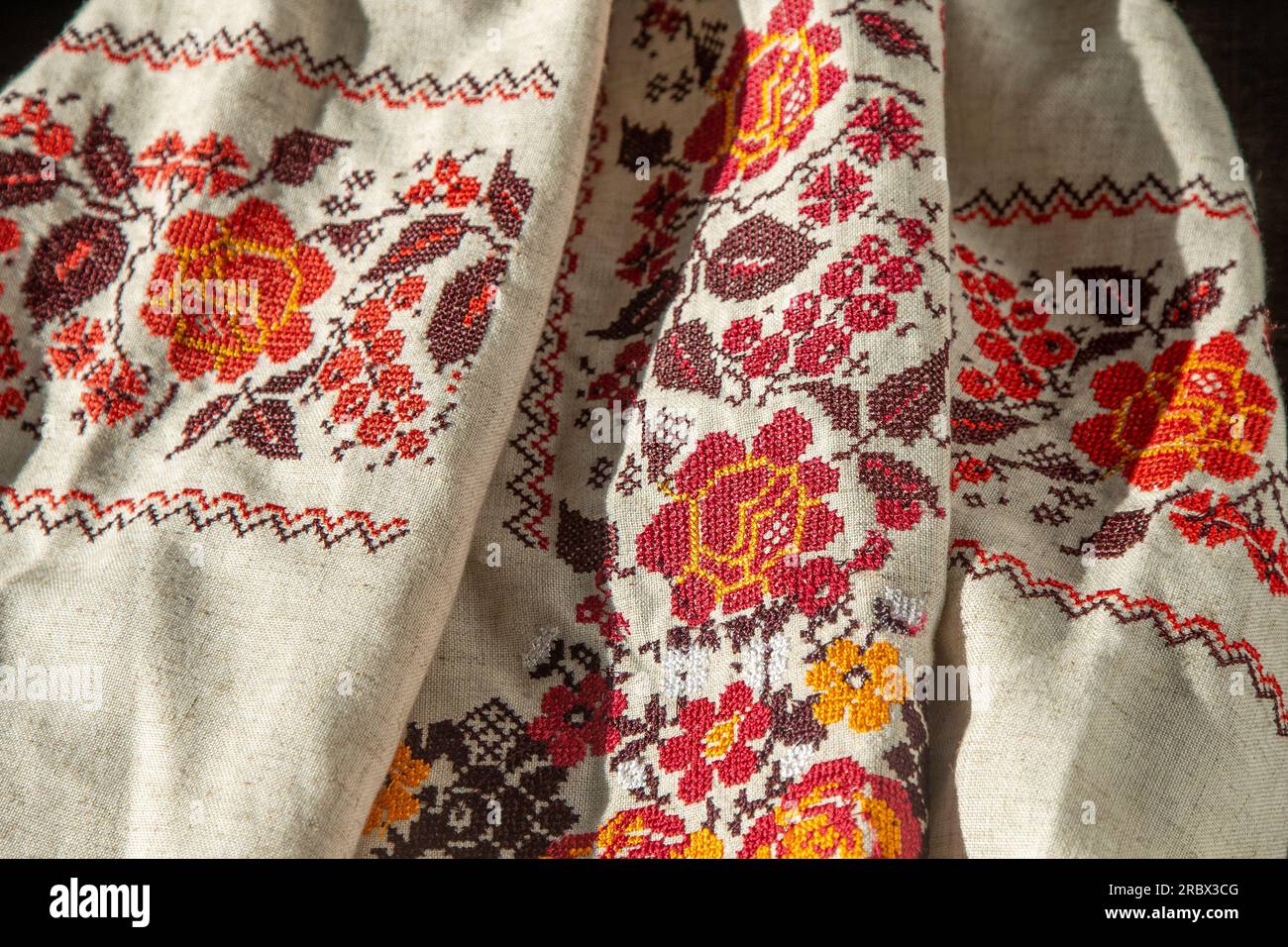Camicia ricamata con abiti ucraini. Sfondo rosso arancione per le filettature. Vyshyvanka è un simbolo dell'Ucraina. Ricamo con cuciture incrociate. Punto nazionale ucraino. Simbolo dell'abbigliamento tradizionale. Foto Stock