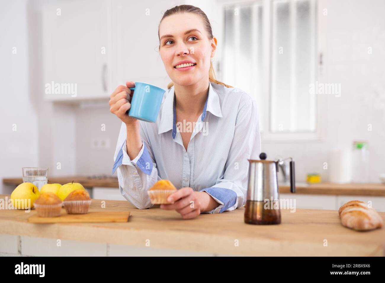 Giovane donna spensierata in camicia da uomo gustando il caffè del mattino a casa Foto Stock