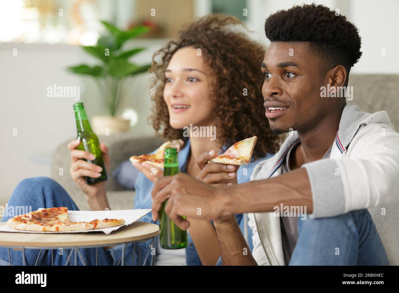 coppia che guarda lo sport in tv mentre mangia la pizza Foto Stock