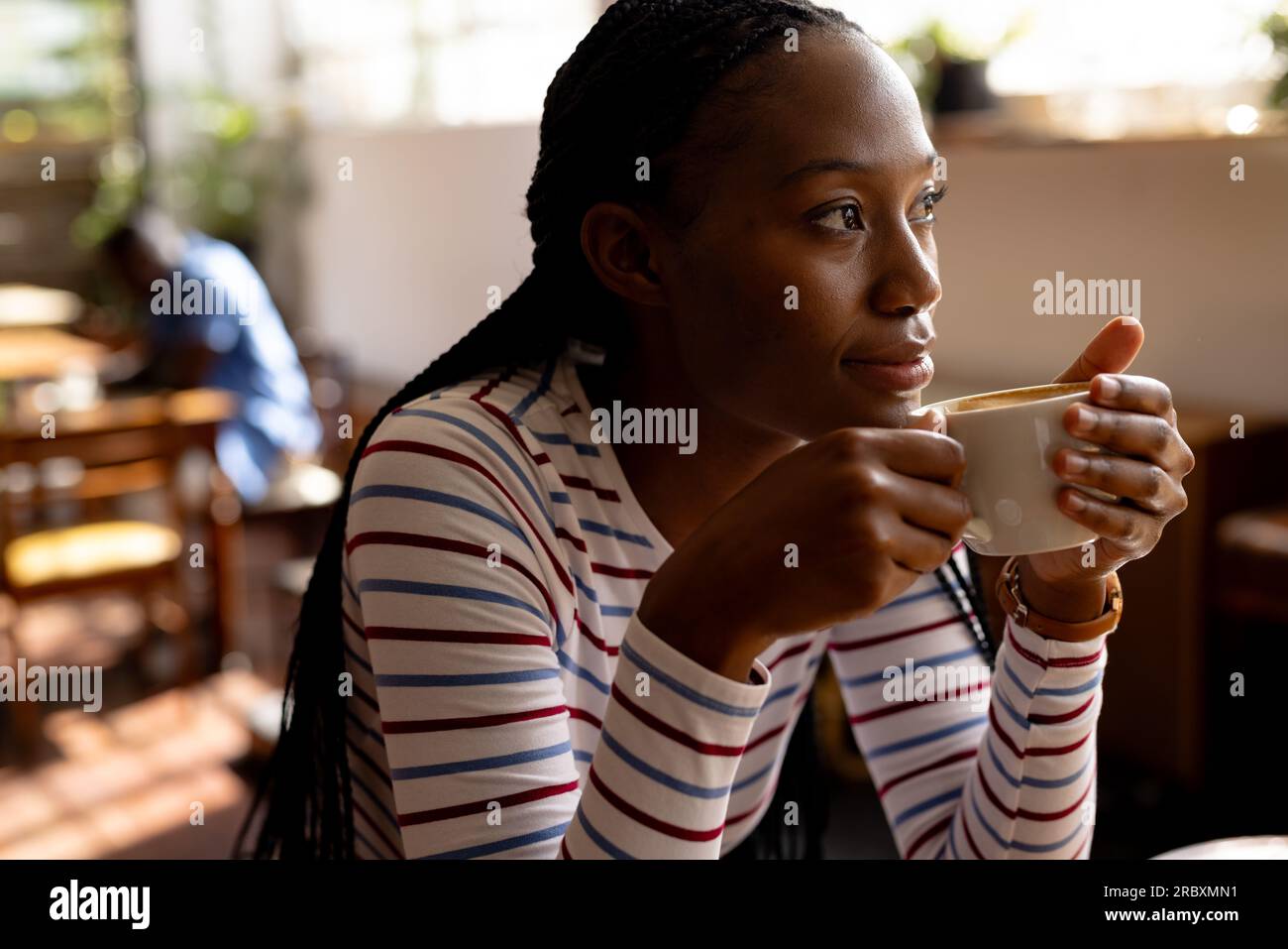 Premurosa donna afro-americana che beve caffè in caffetteria Foto Stock