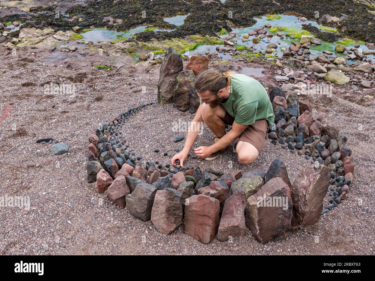 L'artista di terra Jon Foreman crea una scultura di roccia o pietra, European Land Art Festival, Dunbar, East Lothian, Scozia, Regno Unito Foto Stock