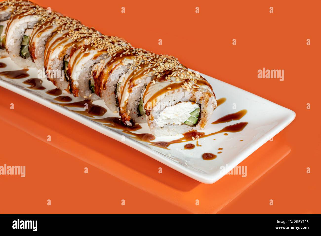 Sushi, panini con caviale, gamberi, tonno e avocado e formaggio Philadelphia, su un piatto bianco. Su uno sfondo colorato. copia spazio Foto Stock