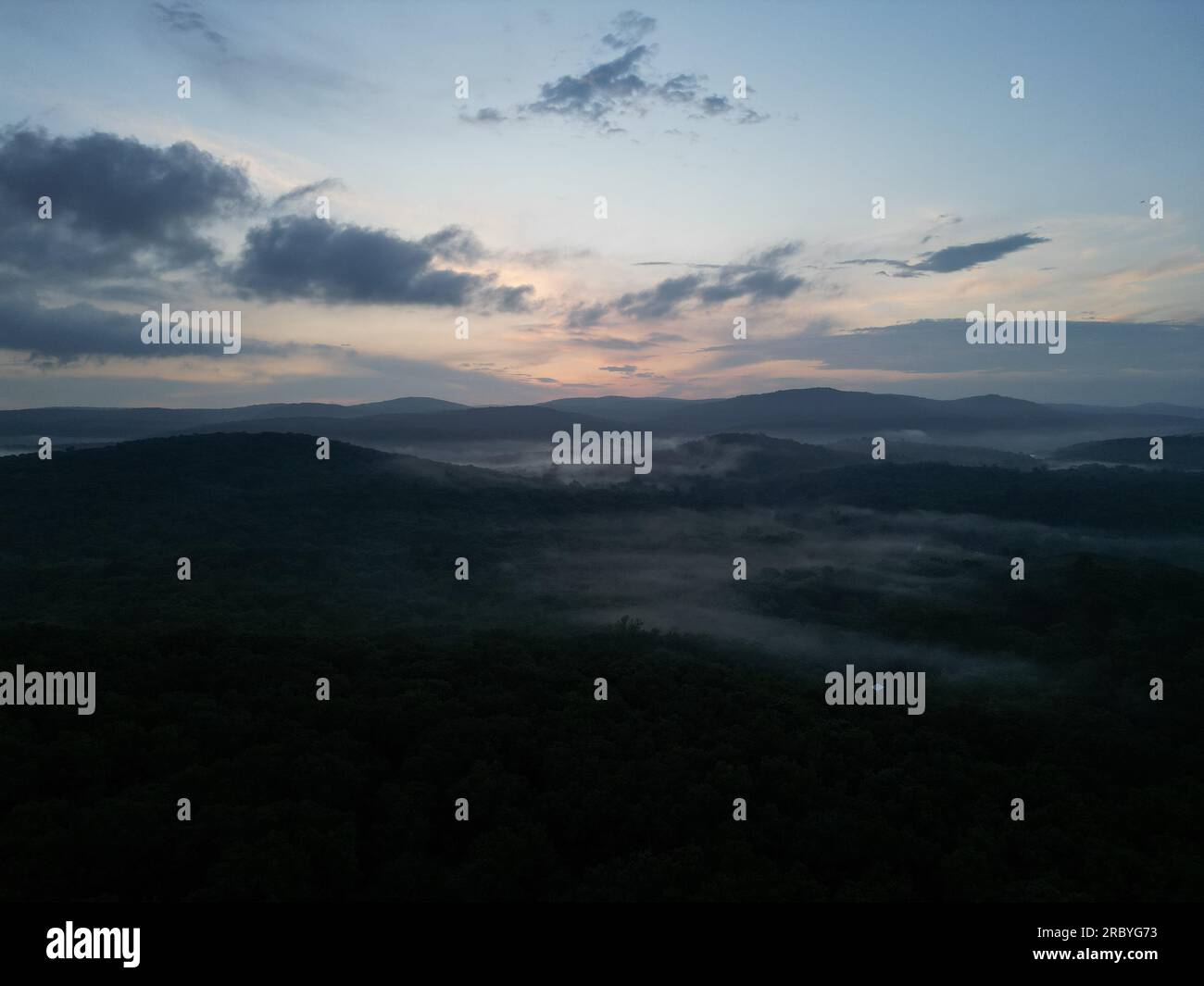 Foto con droni di una valle nebbiosa con colline ondulate durante il tramonto Foto Stock