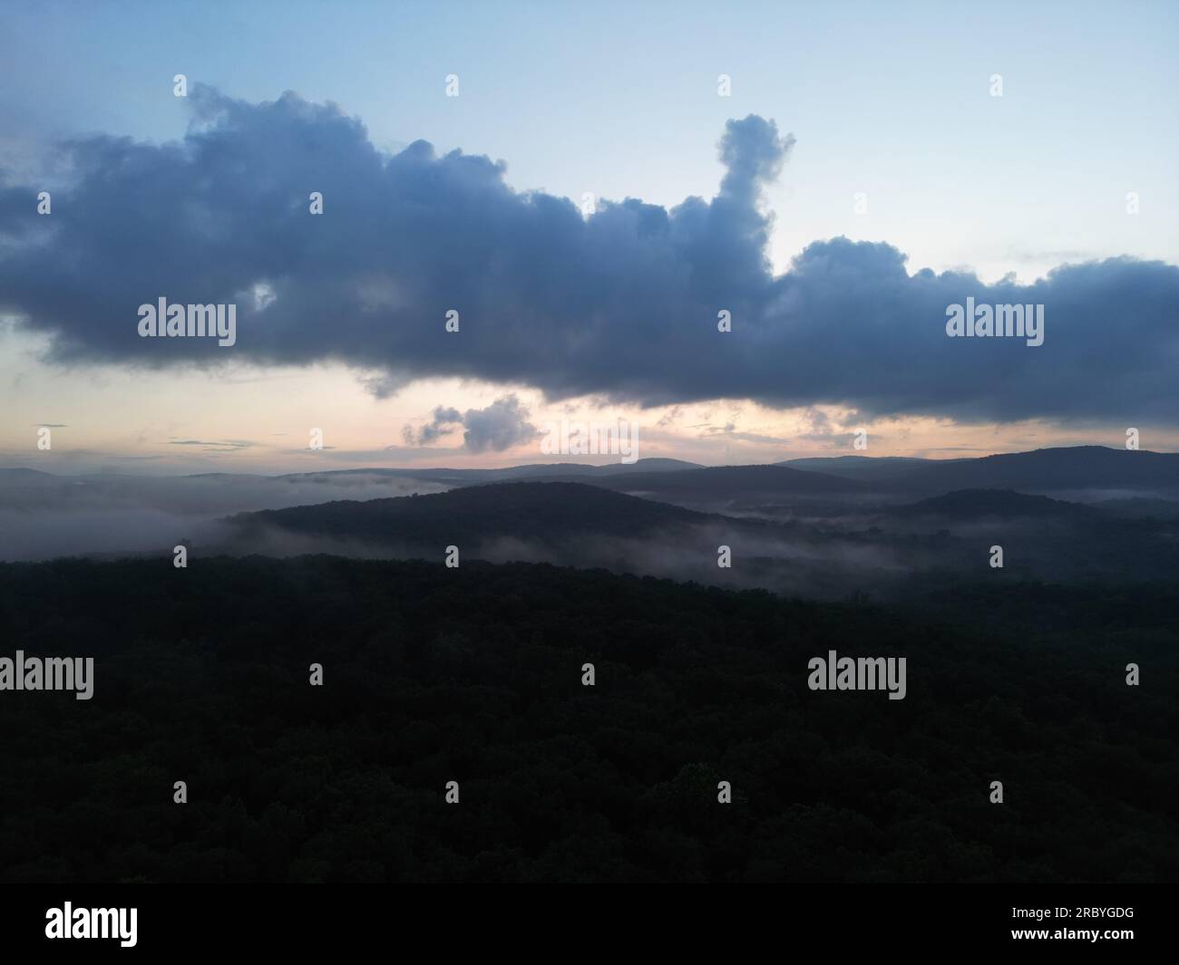 Foto con droni di una valle nebbiosa con colline ondulate durante il tramonto Foto Stock