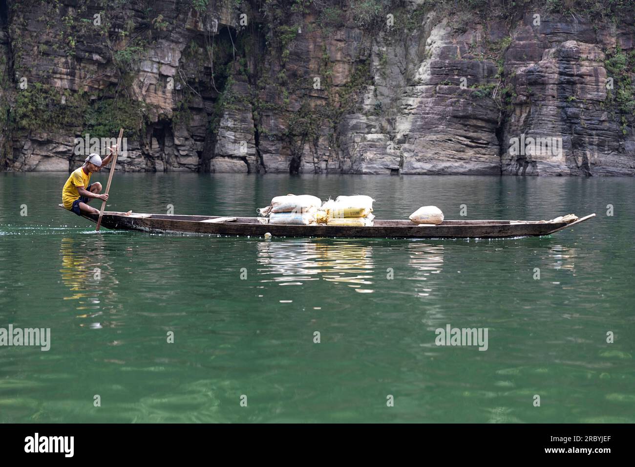 Pescatore pagaiando in una tradizionale barca di legno presso il fiume Umtong, Dawki, Meghala Foto Stock