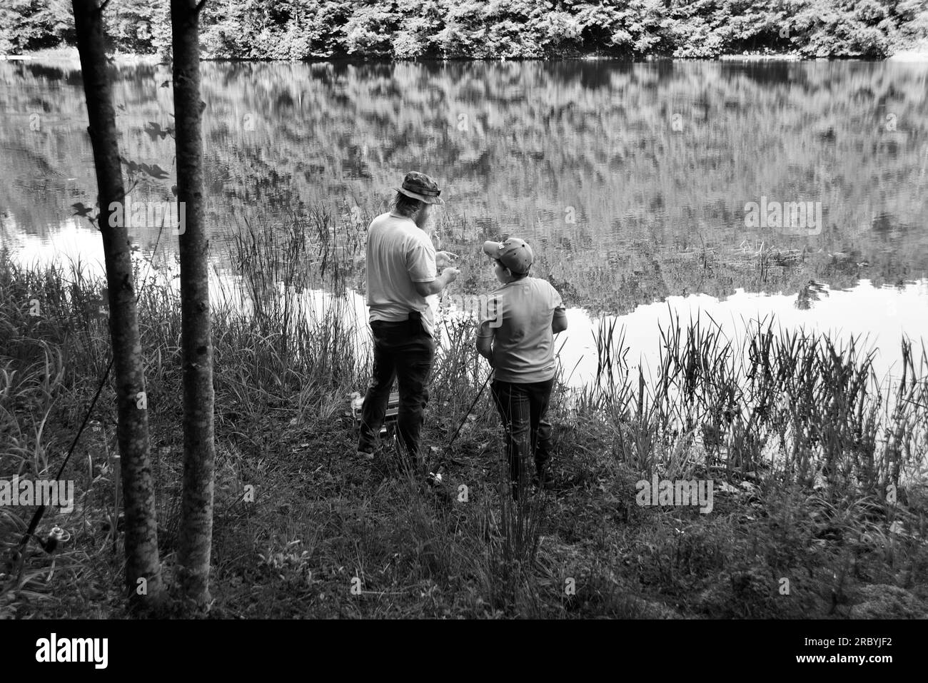 Un uomo e suo figlio pescano accanto ad un lago in Virginia, USA. Foto Stock