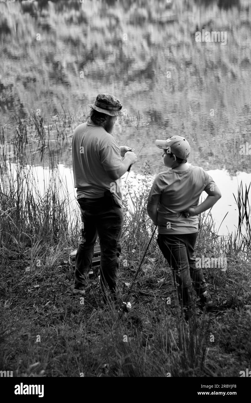 Un uomo e suo figlio pescano accanto ad un lago in Virginia, USA. Foto Stock