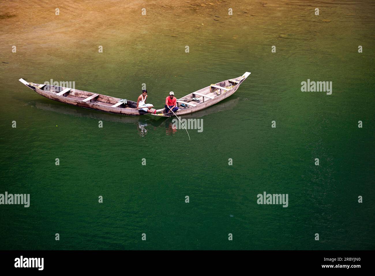 Pescatori locali su tradizionali barche di legno che pescano nel fiume Umngot o Dawki a Meghalaya, India Foto Stock