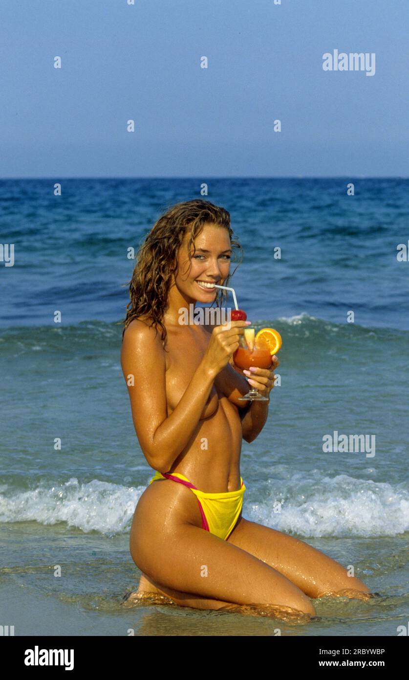 felice bella giovane donna che guarda la fotocamera anteriore beve frutta coktail; acqua di mare e cielo blu sullo sfondo sano attraente silhouette corpo sorridente Foto Stock