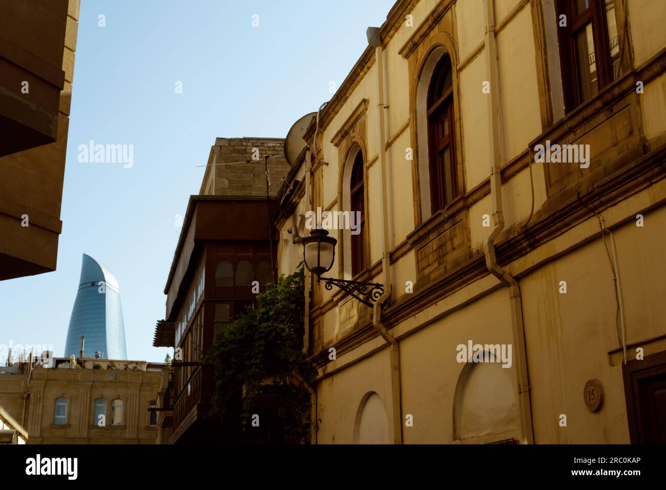 Baku, Azerbaigian - 25 giugno 2023: Uno scorcio di una torre della fiamma, un'icona moderna di Baku, vista attraverso gli edifici storici di Icheri Sheher, il cuore Foto Stock