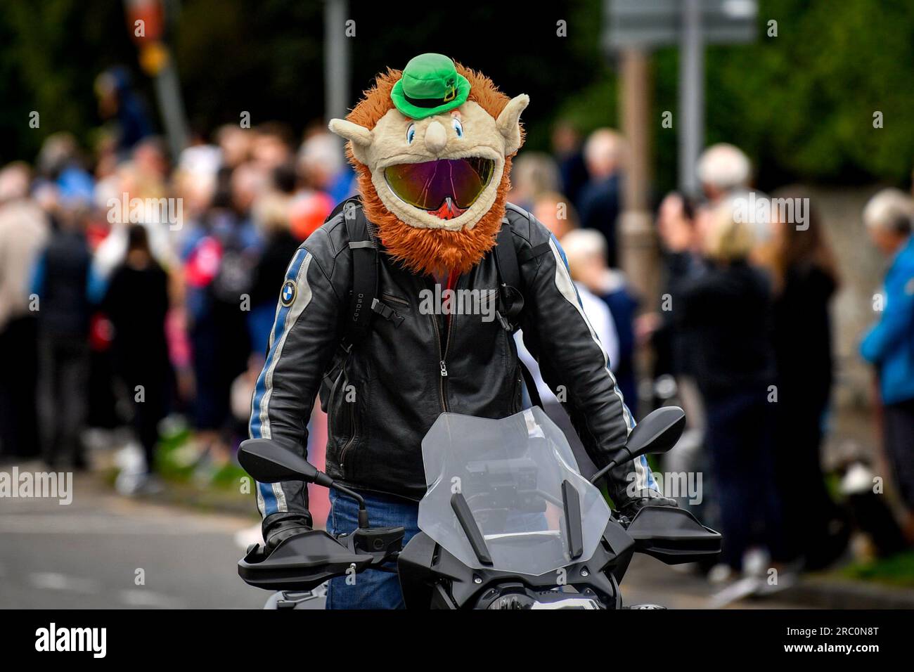 Motociclista che attraversa Edimburgo indossando un divertente casco Leprechaun Crash Foto Stock