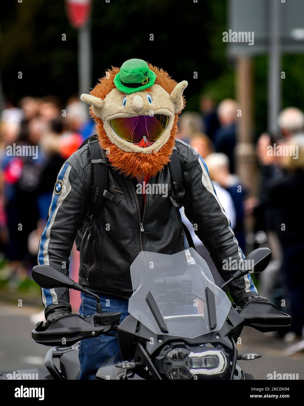 Motociclista che attraversa Edimburgo indossando un divertente casco Leprechaun Crash Foto Stock