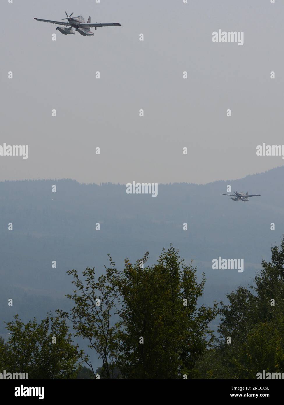 Due aeroplani Water Bomber che combattono gli incendi boschivi nei pressi di Smithers in volo dopo aver accumulato acqua dal vicino lago Tyhee. - Smithers BC.- 09 luglio 2023 Foto Stock