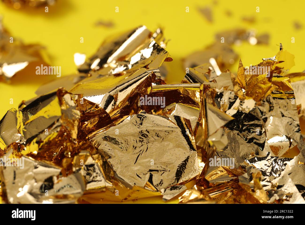 Foglia d'oro commestibile su sfondo giallo, primo piano Foto stock