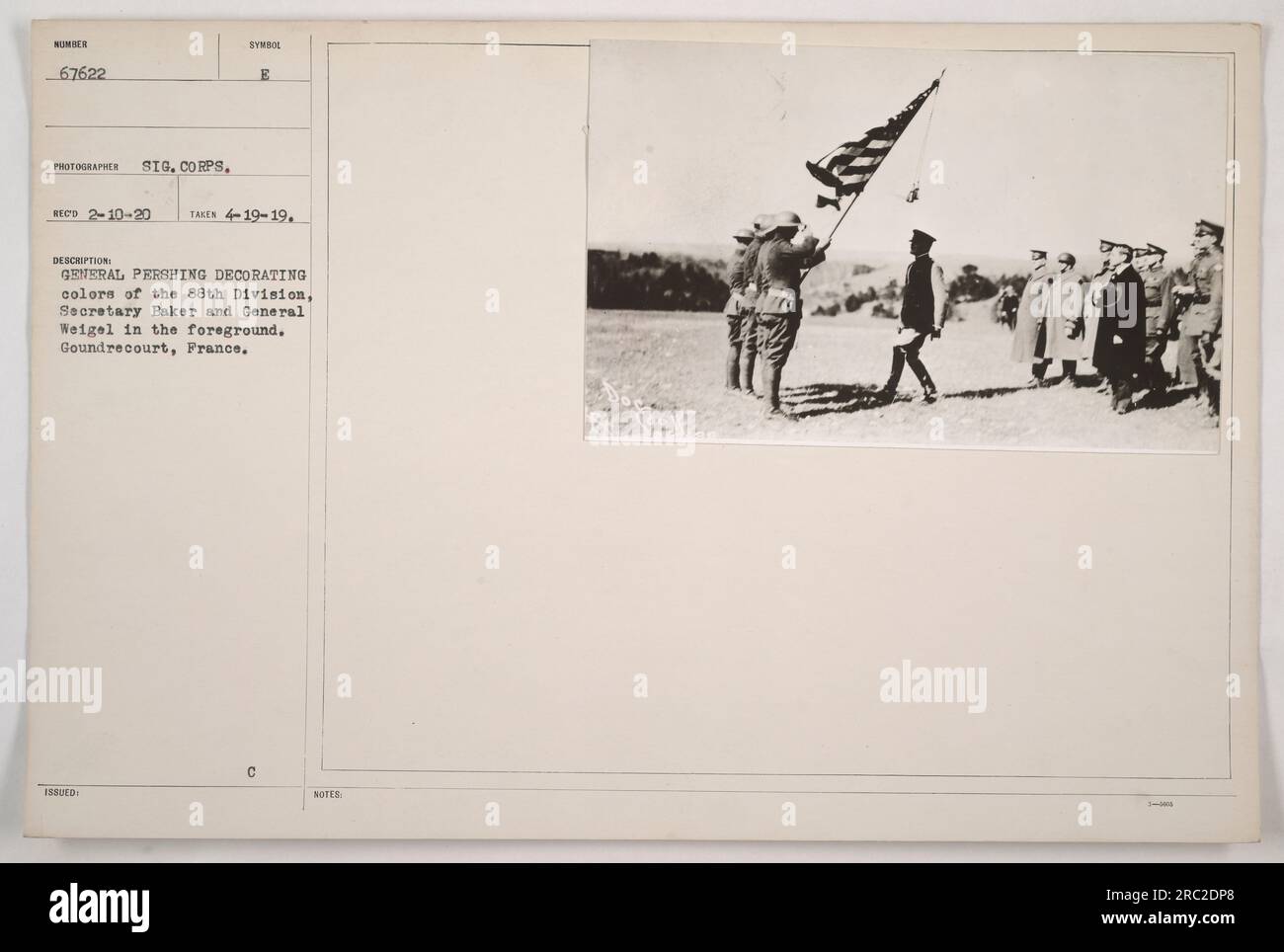 Il generale Pershing partecipa alla cerimonia per decorare i colori della 88a Divisione. Il Segretario Baker e il generale Weigel sono presenti in primo piano. La posizione è Gondrecourt, Francia. Fotografia scattata il 19 aprile 1919 da un fotografo ufficiale del Signal Corps. Il numero di registrazione dell'immagine è 67622. Didascalia emessa con le banconote il 10 febbraio 1920. Foto Stock