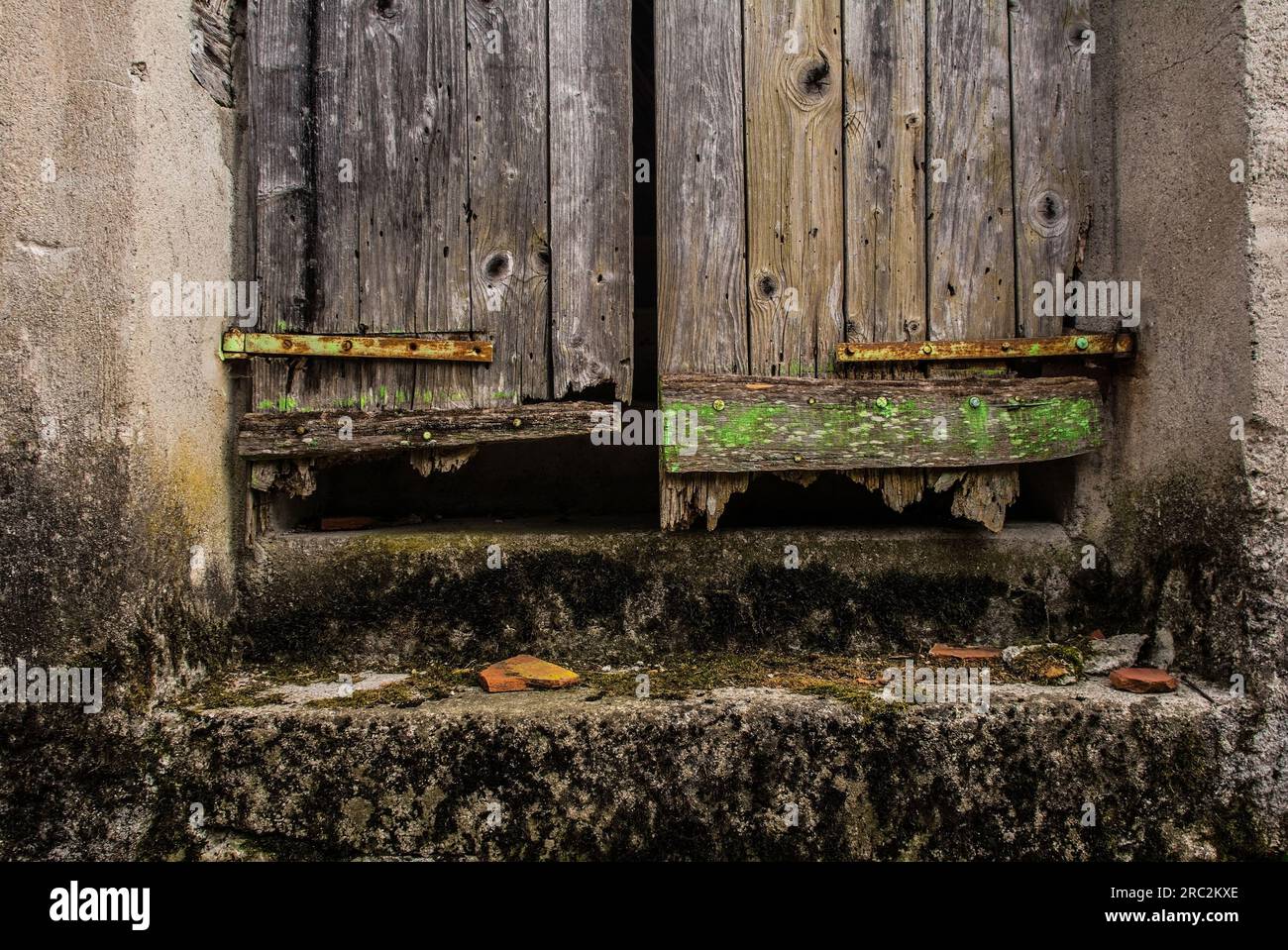 La porta sotto una vecchia porta di legno in uno storico edificio residenziale abbandonato nel villaggio di Trava, nel quartiere Lauco, Udine, Friuli, ne Italia Foto Stock