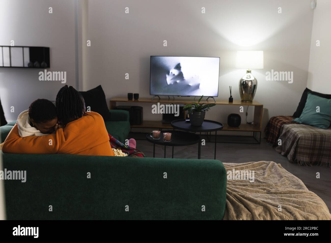 Coppia afroamericana spaventata che si coccola a casa guardando un film spaventoso Foto Stock