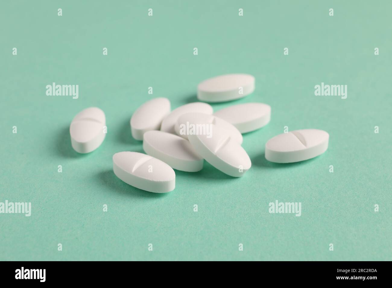 Pila di pillole bianche su sfondo verde, primo piano Foto Stock