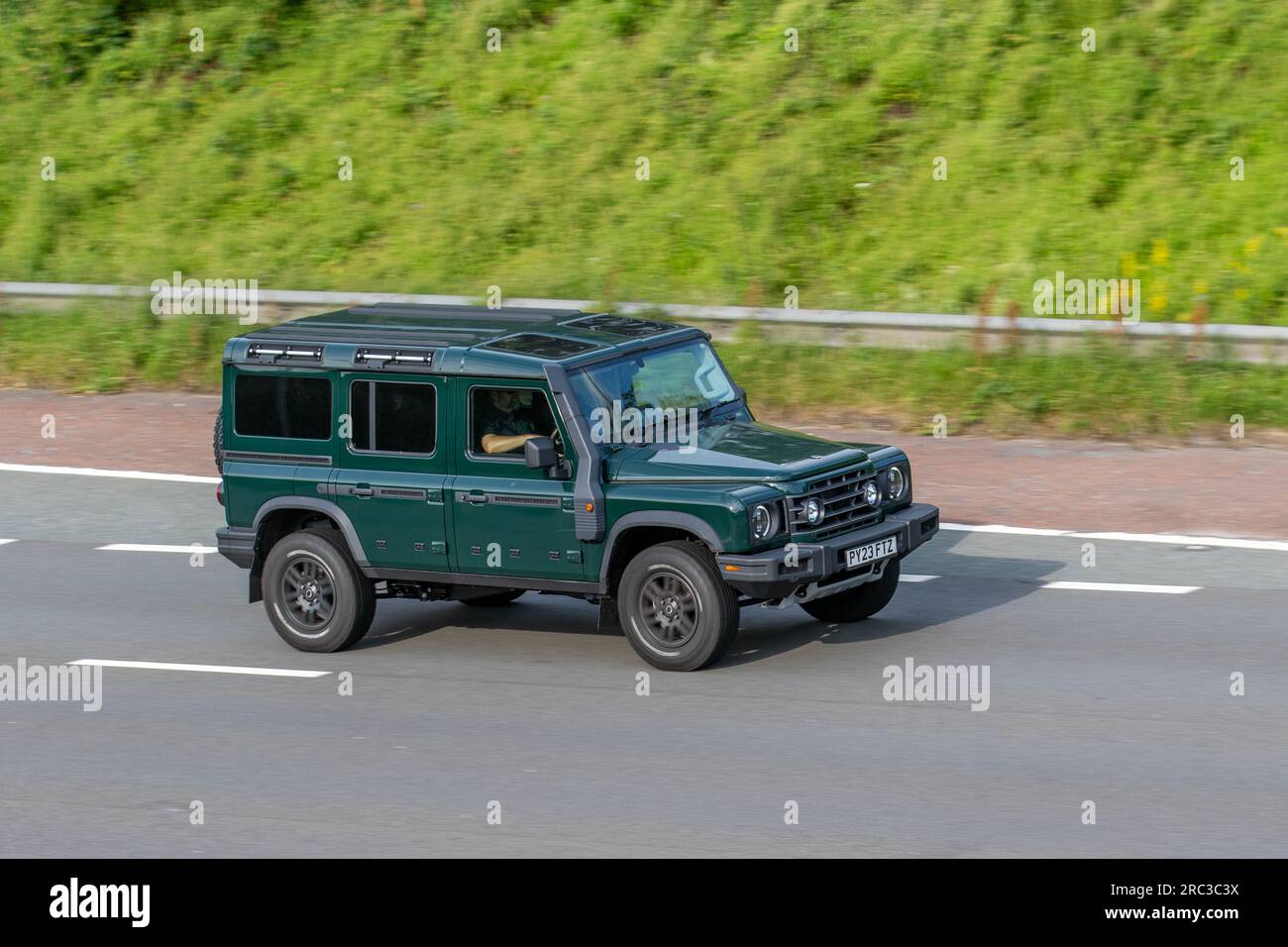 2023 Green Ineos Grenadier Trialmaster ed Auto benzina 2998 cc; viaggia a velocità sostenuta sull'autostrada M6 a Greater Manchester, Regno Unito Foto Stock