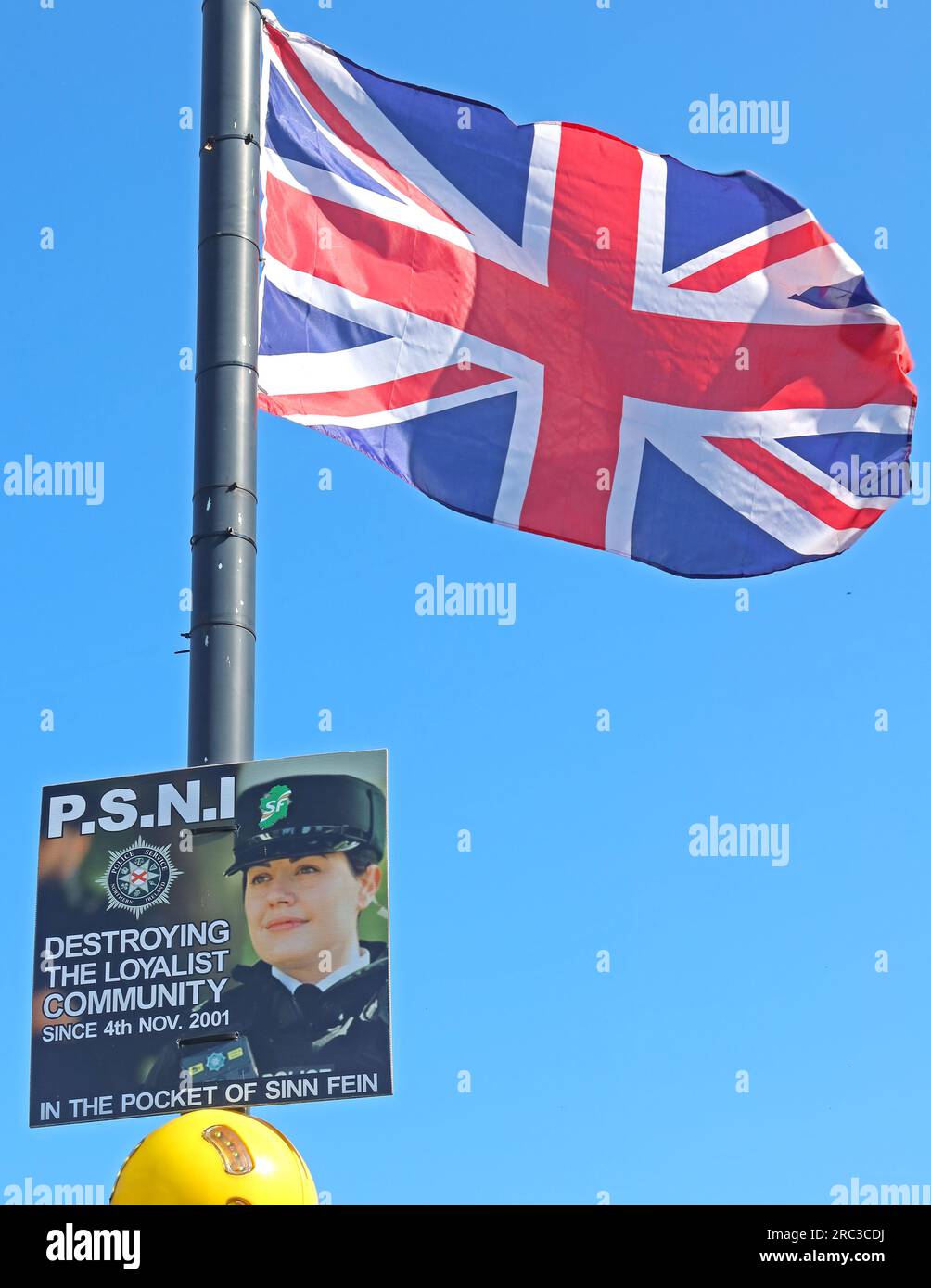 La bandiera dell'Unione Britannica vola a Bushmills, il poster deduce la PSNI come la distruzione della comunità lealista e dal 4 novembre 2001 nella tasca del Sinn Fein, BT57 8QD Foto Stock